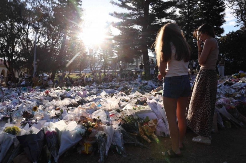 Mourners gather yesterday in front of tributes in memory of the victims of a shooting at Bondi Beach, in Sydney. – AFP Mourners gather yesterday in front of tributes in memory of the victims of a shooting at Bondi Beach, in Sydney. – AFP