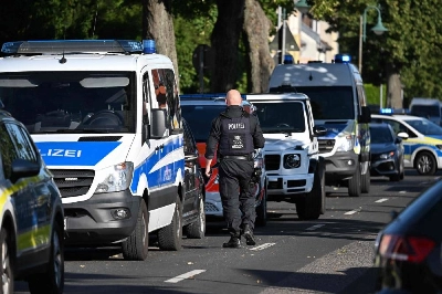A police officer walks near the scene at a school in Gosen-Neu Zittau, south-east of Berlin on August 27, 2026, after two people were killed in a "violent incident" at the school. Local media reported August 27 that an 18-year-old female student and a 30-year-old man had died. Regional public broadcaster RBB and a local daily said that an alarm had been triggered at a secondary school in the town of Gosen-Neu Zittau, with police confirming they were on the scene and that a suspect had been arrested. (Photo by RALF HIRSCHBERGER / AFP) A police officer walks near the scene at a school in Gosen-Neu Zittau, south-east of Berlin on August 27, 2026, after two people were killed in a "violent incident" at the school. Local media reported August 27 that an 18-year-old female student and a 30-year-old man had died. Regional public broadcaster RBB and a local daily said that an alarm had been triggered at a secondary school in the town of Gosen-Neu Zittau, with police confirming they were on the scene and that a suspect had been arrested. (Photo by RALF HIRSCHBERGER / AFP)