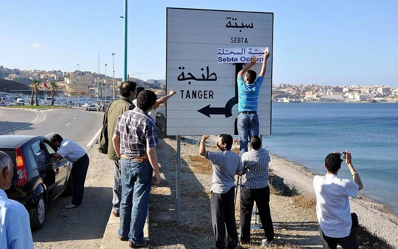 Des jeunes rectifiant le panneau de signalisation, en ajoutant le mot "occupée" devant le nom de Sebta.