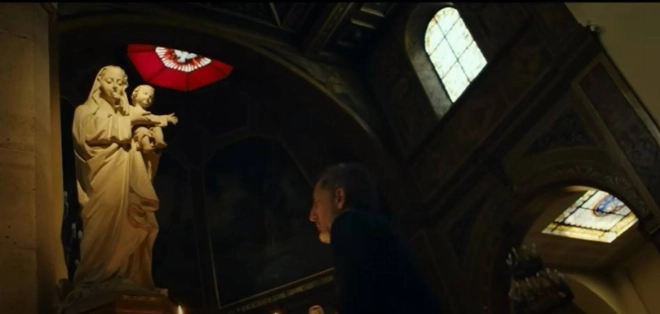 Gad Elmaleh face à la statut de la vierge Marie à l'église