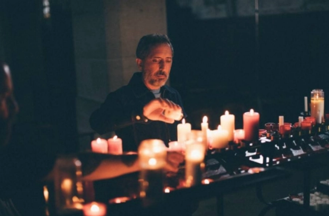 Gad Elmaleh allumant des bougies à l'église.