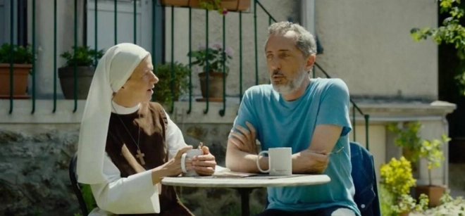 Gad Elmaleh assis avec une religieuse dans Reste un peu.