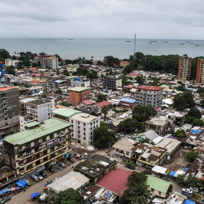 Shipping vessels sit on the waterway beyond commercial and residential buildings on the city skyline in Conakry, Guinea, on Saturday, Sept. 5, 2015. While Guinea produces bauxite, which is refined into aluminum, and has vast iron-ore deposits, its mining potential has been largely untapped because of political instability and a lack of infrastructure. Photographer: Waldo Swiegers/Bloomberg via Getty Images