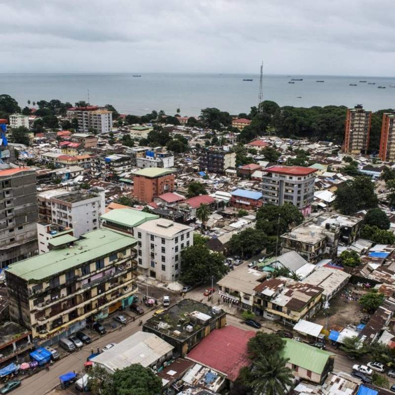 Shipping vessels sit on the waterway beyond commercial and residential buildings on the city skyline in Conakry, Guinea, on Saturday, Sept. 5, 2015. While Guinea produces bauxite, which is refined into aluminum, and has vast iron-ore deposits, its mining potential has been largely untapped because of political instability and a lack of infrastructure. Photographer: Waldo Swiegers/Bloomberg via Getty Images