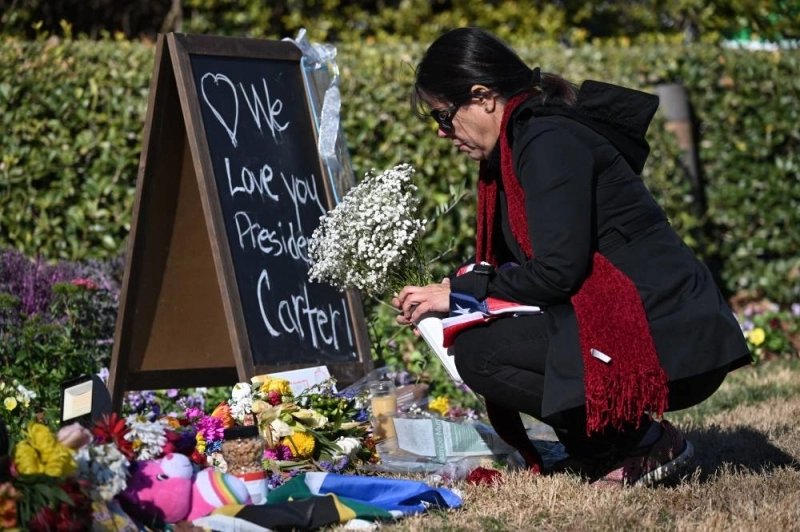 Cette américaine, éplorée, dépose des fleurs devant un mémorial en hommage à l'ancien président des États-Unis, Jimmy Carter, devant le Carter Presidential Center à Atlanta, en Géorgie, le 4 janvier 2025. Ph. AFP