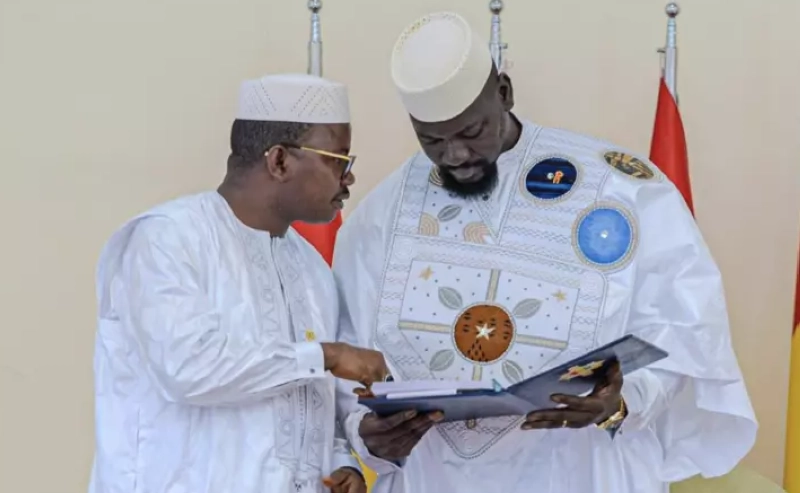 Le président du Conseil national de transition, Dr. Dansa Kourouma (gauche) remet au président guinéen Mamadi Doumbouya (droite) le projet de nouvelle Constitution guinéenne, le 26 juin 2025 à Conakry