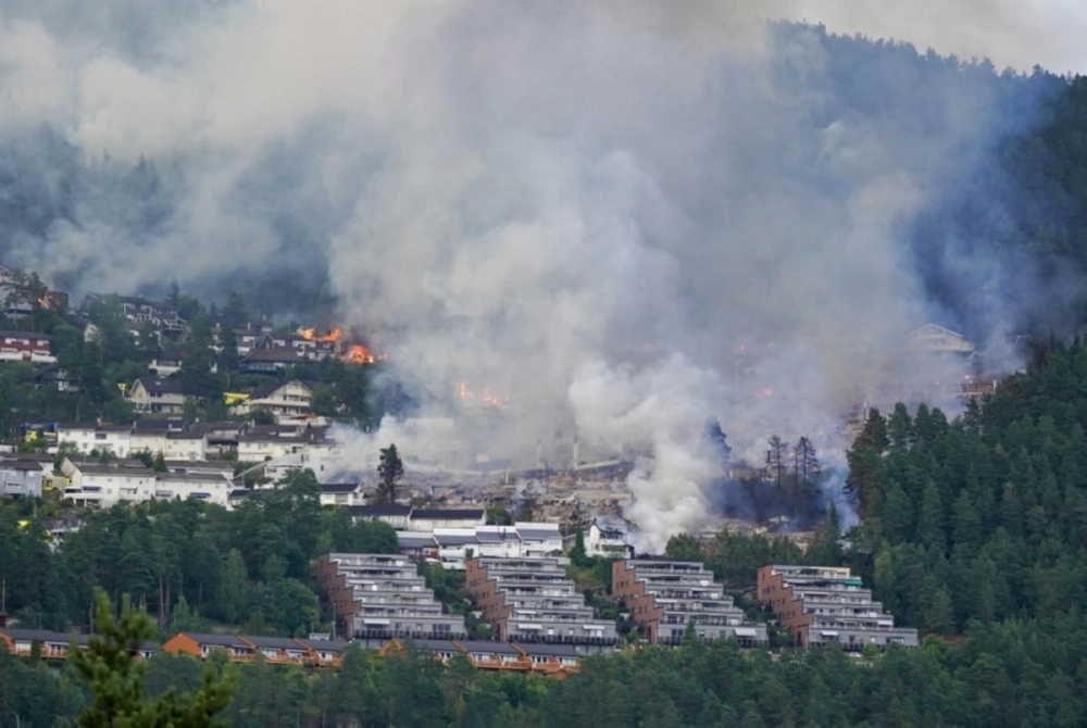 Smoke and flames rise from a huge fire that has spread from terraced houses by the Krokstadelva in Drammen. — EPA