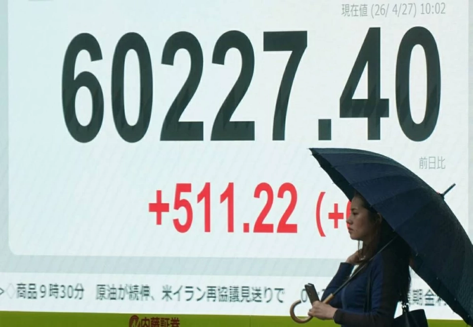 امرأة تمر أمام لوحة إلكترونية تعرض مؤشر نيكاي للأسهم في أحد شوارع طوكيو (27 أبريل 2026 / أ.ف.ب)