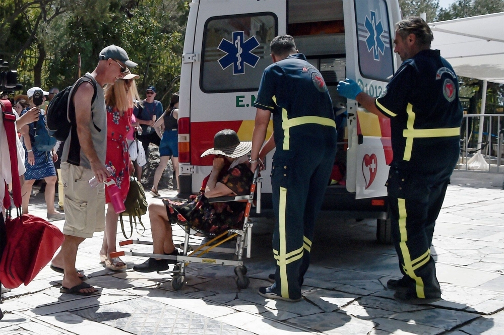 Medics help a woman who had passed out from the heat in Athens, Greece, on Thursday. Medics help a woman who had passed out from the heat in Athens, Greece, on Thursday.