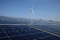 A wind turbine stands next to solar panels at a Banpu Power solar plant in Awaji, Hyogo Prefecture. | Bloomberg