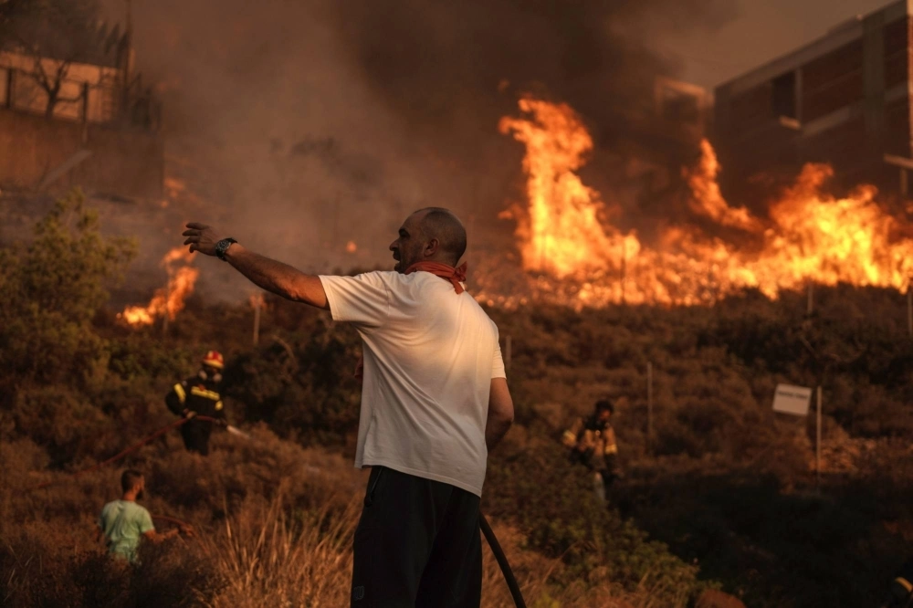 Firefighters and volunteers work to extinguish a burning field during a wildfire in Saronida, south of Athens, Greece, on July 17. Firefighters and volunteers work to extinguish a burning field during a wildfire in Saronida, south of Athens, Greece, on July 17.