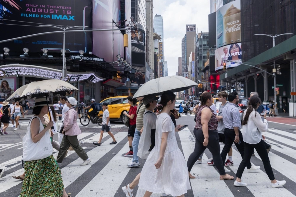 Pedestrians hold umbrellas for protection from the sun during a heat wave in New York on Thursday. Pedestrians hold umbrellas for protection from the sun during a heat wave in New York on Thursday.