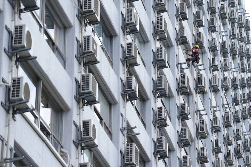 A worker washes windows next to air conditioning units at an apartment building in Tokyo on July 21. A worker washes windows next to air conditioning units at an apartment building in Tokyo on July 21.