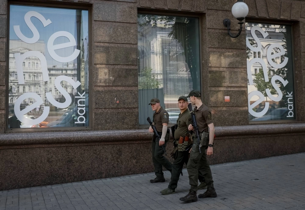 Military personnel patrol a street outside a branch of Ukraine's Sense Bank in central Kyiv in June. Military personnel patrol a street outside a branch of Ukraine's Sense Bank in central Kyiv in June.