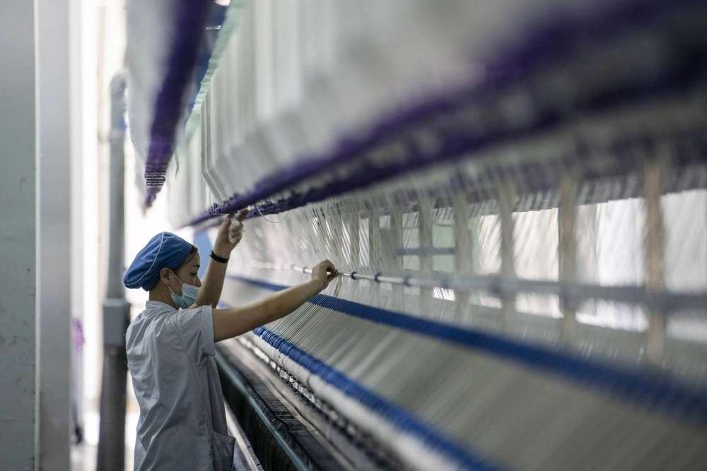 A worker stands in front of a machine on a yarn production line in Putian, Fujian province, China, in February 2021. A worker stands in front of a machine on a yarn production line in Putian, Fujian province, China, in February 2021.