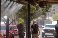Residents walk through misters during a heat wave in Phoenix, Arizona, on July 20. | Bloomberg