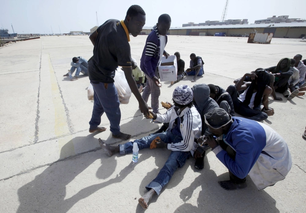 Migrants at a base near Tripoli hand out food to other migrants after they were detained by the Libyan navy in September 2015. 
 Migrants at a base near Tripoli hand out food to other migrants after they were detained by the Libyan navy in September 2015.