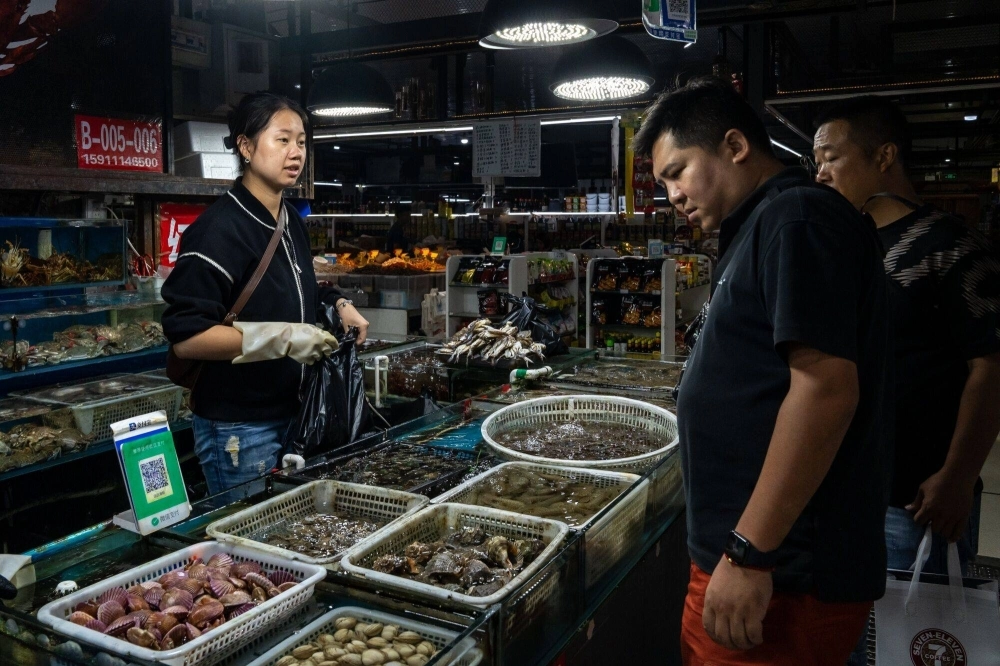 Customers shop at a seafood market in Beijing on Friday. Customers shop at a seafood market in Beijing on Friday.