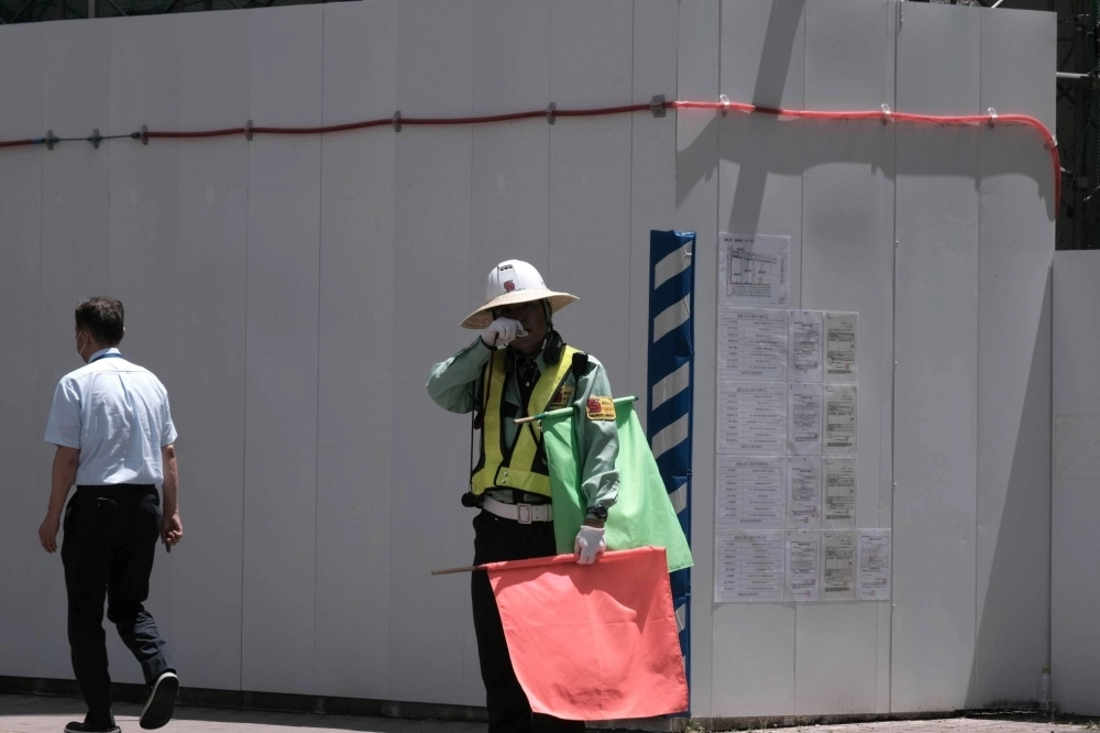 A worker directing traffic in front of a construction site in the city of Fukushima on July 6. A worker directing traffic in front of a construction site in the city of Fukushima on July 6.