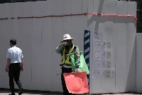 A worker directing traffic in front of a construction site in the city of Fukushima on July 6. | Bloomberg