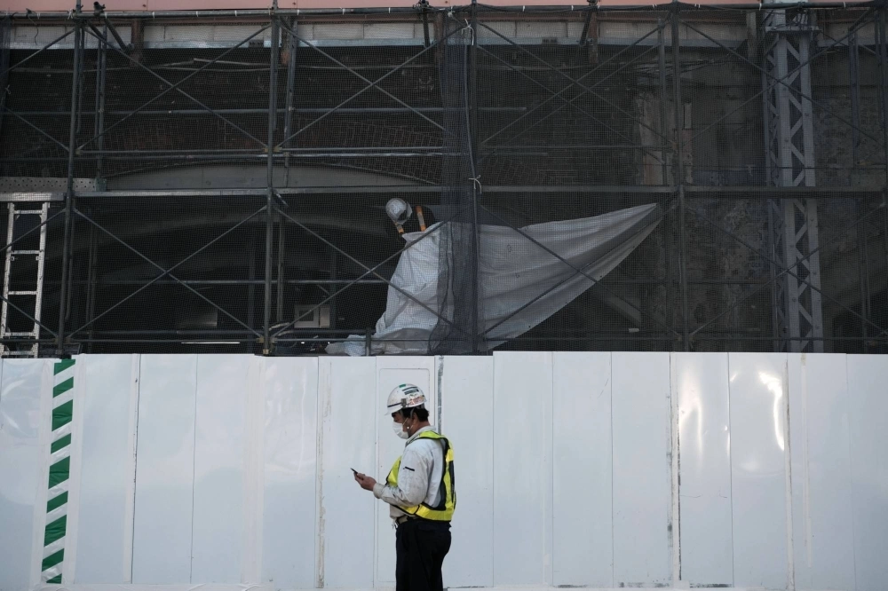 A worker looks at a smartphone in front of a construction site in the Shimbashi district in Tokyo in May 2020. A worker looks at a smartphone in front of a construction site in the Shimbashi district in Tokyo in May 2020.