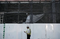A worker looks at a smartphone in front of a construction site in the Shimbashi district in Tokyo in May 2020. | Bloomberg