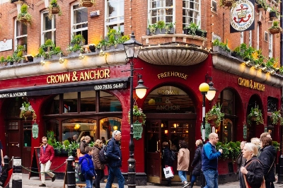 Tourists walk in front of Crown and Anchor pub on Neal Street in London in 2018. Pubs are big part of British culture.  Tourists walk in front of Crown and Anchor pub on Neal Street in London in 2018. Pubs are big part of British culture.