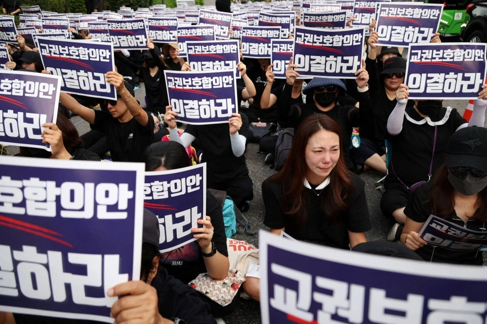 A South Korean teacher reacts as others chant slogans during a protest to demand better protection of their rights and to mourn a young teacher found dead in July in an apparent suicide, in Seoul on Monday. The signs read "Vote for an agreement on the protection of teachers' rights." A South Korean teacher reacts as others chant slogans during a protest to demand better protection of their rights and to mourn a young teacher found dead in July in an apparent suicide, in Seoul on Monday. The signs read "Vote for an agreement on the protection of teachers' rights."