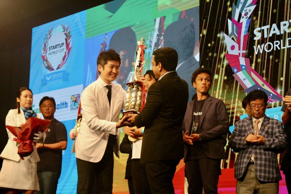 Aillis CEO Sho Okiyama receives the first place award from Pegasus Tech Ventues founder and CEO Anis Uzzaman at the Startup World Cup Tokyo preliminary on Friday. Aillis CEO Sho Okiyama receives the first place award from Pegasus Tech Ventues founder and CEO Anis Uzzaman at the Startup World Cup Tokyo preliminary on Friday.