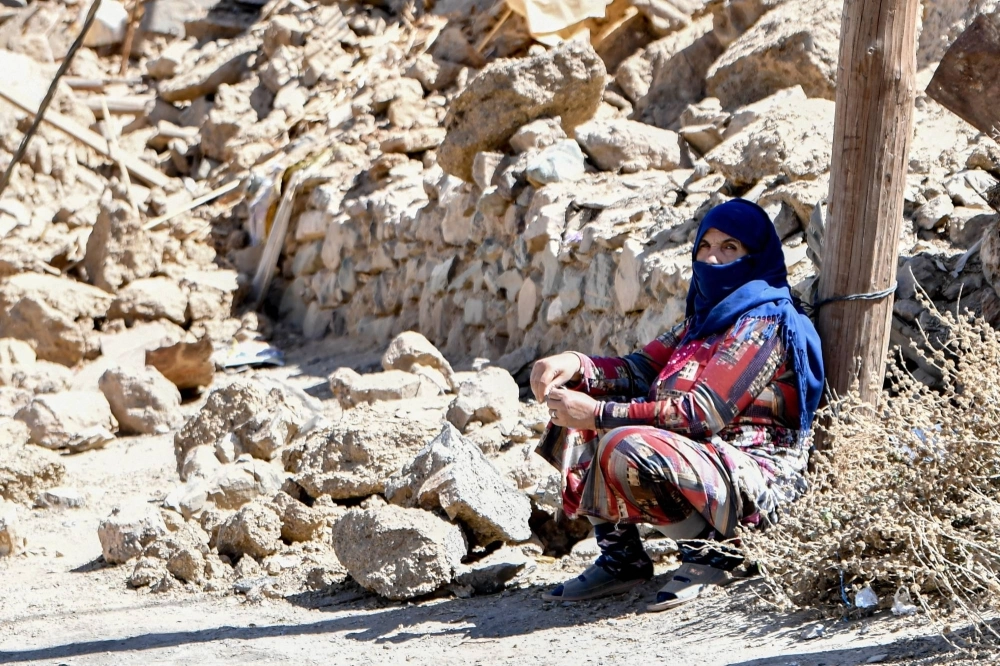 A woman sits near debris in the earthquake-hit village of Ardouz, in Morocco's Amizmiz region, on Thursday. A woman sits near debris in the earthquake-hit village of Ardouz, in Morocco's Amizmiz region, on Thursday.