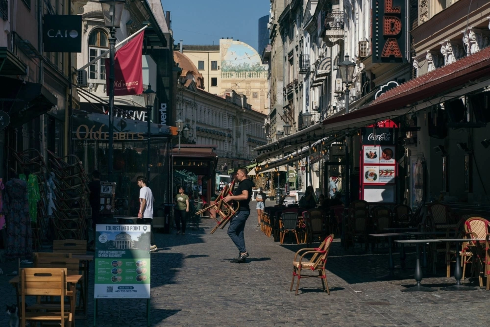 An employee prepares tables and chairs outside a restaurant in Bucharest, Romania. An employee prepares tables and chairs outside a restaurant in Bucharest, Romania.