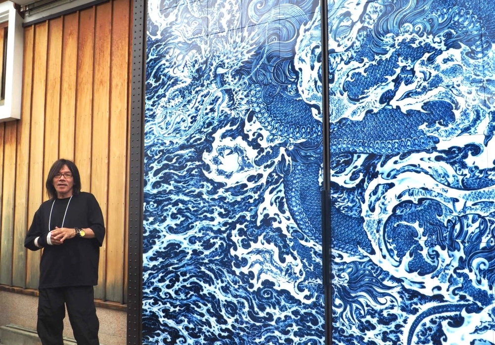 Yuki Hayama tells visitors about his dragon mural, an enlarged print of his ceramic work, showcased on the doors of the Masuda Sake Brewery. Yuki Hayama tells visitors about his dragon mural, an enlarged print of his ceramic work, showcased on the doors of the Masuda Sake Brewery.