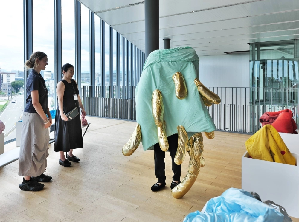 French artist Audrey Gambier (far left) observes a visitor to Go For Kogei’s “Material Imagination and Etiological Narrative: Material, Data, Fantasy” exhibition wearing one of her works at Toyama Prefectural Museum of Art and Design.  French artist Audrey Gambier (far left) observes a visitor to Go For Kogei’s “Material Imagination and Etiological Narrative: Material, Data, Fantasy” exhibition wearing one of her works at Toyama Prefectural Museum of Art and Design.