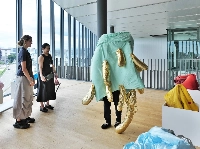 French artist Audrey Gambier (far left) observes a visitor to Go For Kogei’s “Material Imagination and Etiological Narrative: Material, Data, Fantasy” exhibition wearing one of her works at Toyama Prefectural Museum of Art and Design.  |  MASAHIRO KATANO