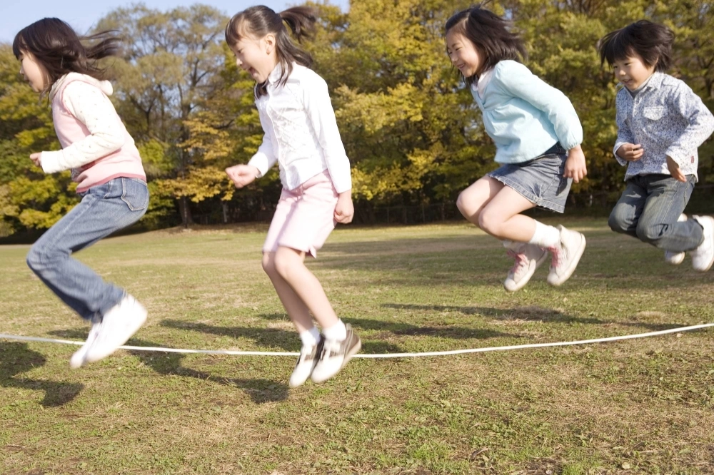 Children jump rope in a park. Young people with developmental coordination disorder (DCD) can have difficulties in jumping rope, throwing a ball or doing other common physical activities. Children jump rope in a park. Young people with developmental coordination disorder (DCD) can have difficulties in jumping rope, throwing a ball or doing other common physical activities.