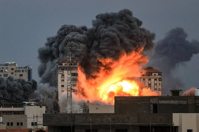 People standing on a rooftop watch as a ball of fire and smoke rises above a building in Gaza City, Gaza Strip, on Saturday during an Israeli airstrike.  People standing on a rooftop watch as a ball of fire and smoke rises above a building in Gaza City, Gaza Strip, on Saturday during an Israeli airstrike.