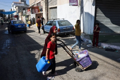 Palestinians carry empty bottles and containers as they look for water at the Rafah refugee camp in the southern Gaza Strip on Monday.  Palestinians carry empty bottles and containers as they look for water at the Rafah refugee camp in the southern Gaza Strip on Monday.