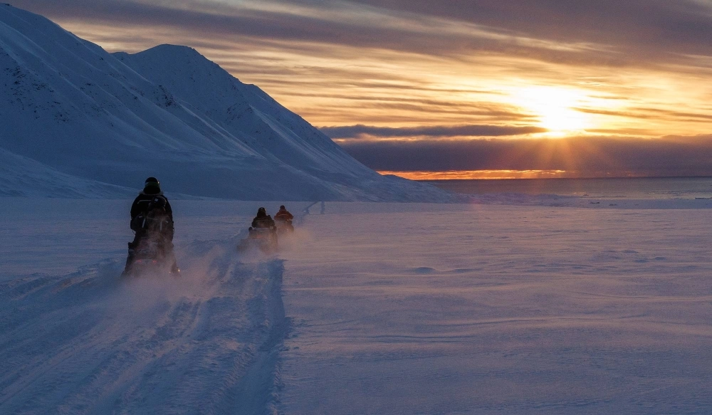 Scientists drive their snowmobiles across the arctic. Scientists drive their snowmobiles across the arctic.