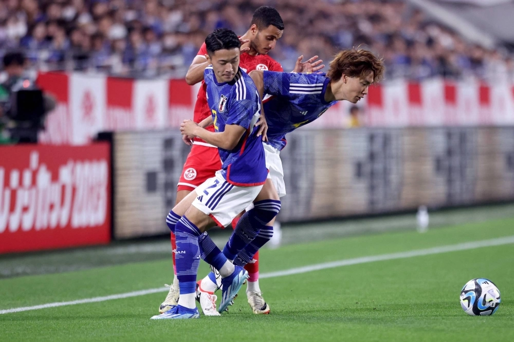 Ko Itakura (right) and Yukinari Sugawara fight for the ball with Tunisia's Elies Ashley during an international friendly football match between Japan and Tunisia in Kobe on Oct. 17. Ko Itakura (right) and Yukinari Sugawara fight for the ball with Tunisia's Elies Ashley during an international friendly football match between Japan and Tunisia in Kobe on Oct. 17.