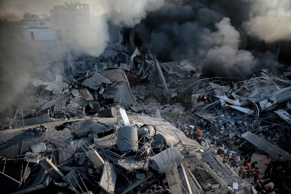Smoke rises from a leveled building as people gather amid the destruction in the aftermath of an Israeli strike on Gaza City on Thursday. Smoke rises from a leveled building as people gather amid the destruction in the aftermath of an Israeli strike on Gaza City on Thursday.
