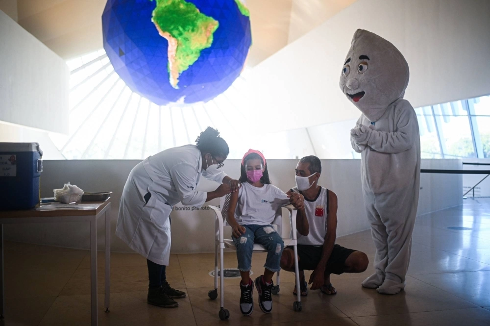 A health care worker administers the COVID-19 vaccine to a child in Rio de Janeiro in January 2022.  A health care worker administers the COVID-19 vaccine to a child in Rio de Janeiro in January 2022.