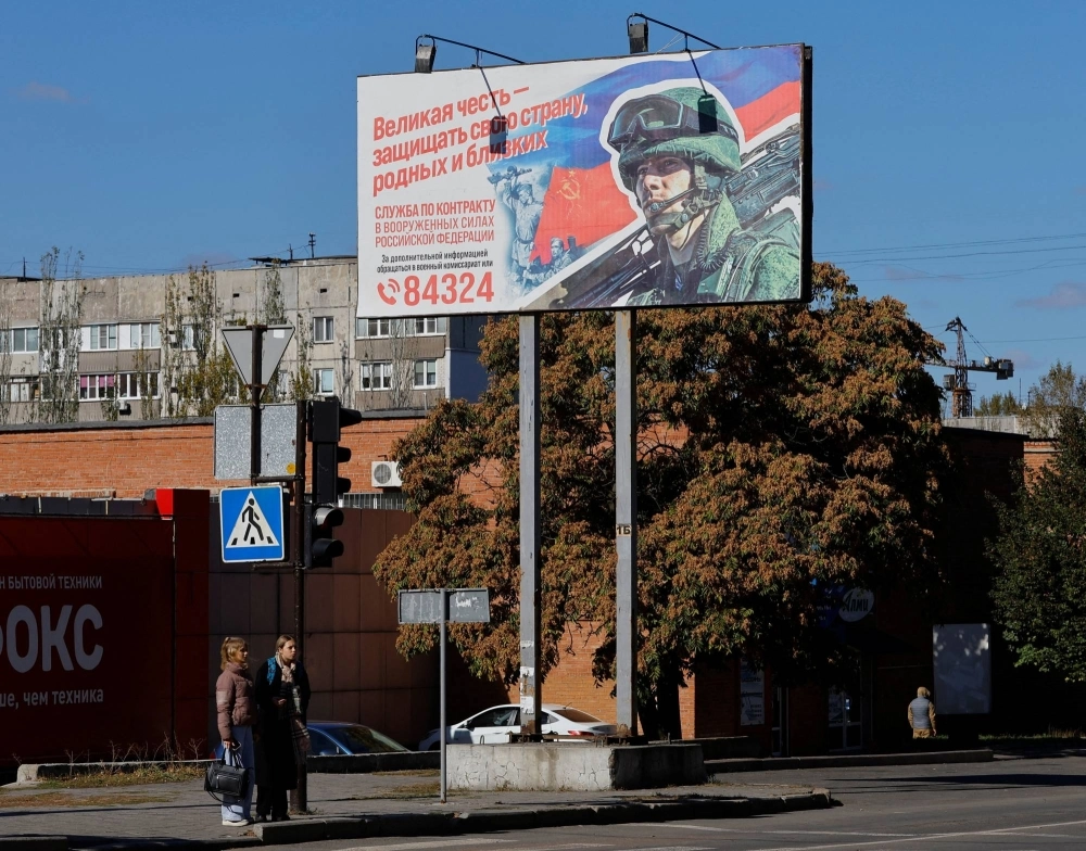 People stand next to a board promoting military service in Donetsk, Russian-controlled Ukraine, on Oct. 11. A Brooklyn man and a Montreal couple have been charged with attempting to smuggle tech to Russia to support the Kremlin's invasion of Ukraine. People stand next to a board promoting military service in Donetsk, Russian-controlled Ukraine, on Oct. 11. A Brooklyn man and a Montreal couple have been charged with attempting to smuggle tech to Russia to support the Kremlin's invasion of Ukraine.