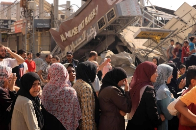 People queue for bread in front of a bakery that was partially destroyed in an Israeli strike, in the Nuseirat refugee camp in the central Gaza Strip, on Thursday. People queue for bread in front of a bakery that was partially destroyed in an Israeli strike, in the Nuseirat refugee camp in the central Gaza Strip, on Thursday.