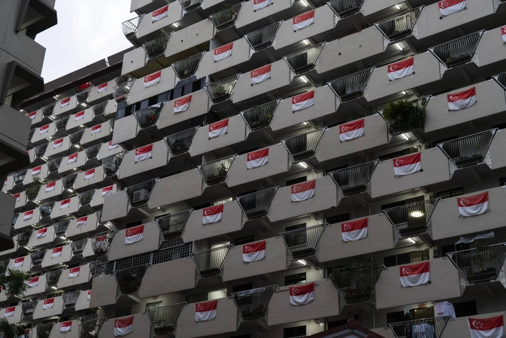Singapore national flags hang from the facade of a Housing & Development Board public housing estate in the Selegie area of Singapore, in 2021. Singapore national flags hang from the facade of a Housing & Development Board public housing estate in the Selegie area of Singapore, in 2021.