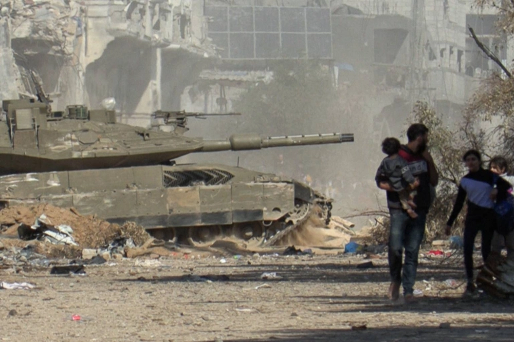 An Israeli armored vehicle rolls past Palestinians fleeing Gaza City, in the Gaza Strip, on foot amid ongoing battles between Israel and the Palestinian Hamas militants on Saturday in this image taken from video. An Israeli armored vehicle rolls past Palestinians fleeing Gaza City, in the Gaza Strip, on foot amid ongoing battles between Israel and the Palestinian Hamas militants on Saturday in this image taken from video.