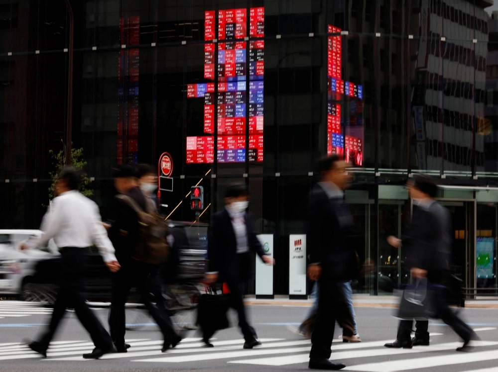 Pedestrians walk past an electronic board displaying various companies' share prices, in a business district in Tokyo on Oct. 31. Pedestrians walk past an electronic board displaying various companies' share prices, in a business district in Tokyo on Oct. 31.