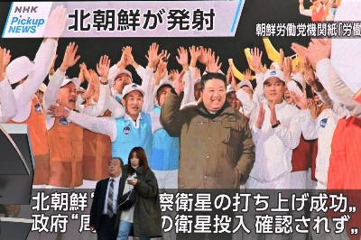 Pedestrians walk past a screen displaying North Korean leader Kim Jong Un celebrating after the launch of a military reconnaissance satellite, in Tokyo's Akihabara district on Wednesday. Pedestrians walk past a screen displaying North Korean leader Kim Jong Un celebrating after the launch of a military reconnaissance satellite, in Tokyo's Akihabara district on Wednesday.