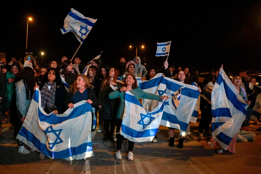 Israeli supporters hold flags hostages arrive at Ofakim army base in southern Israel on Thursday. Israeli supporters hold flags hostages arrive at Ofakim army base in southern Israel on Thursday.