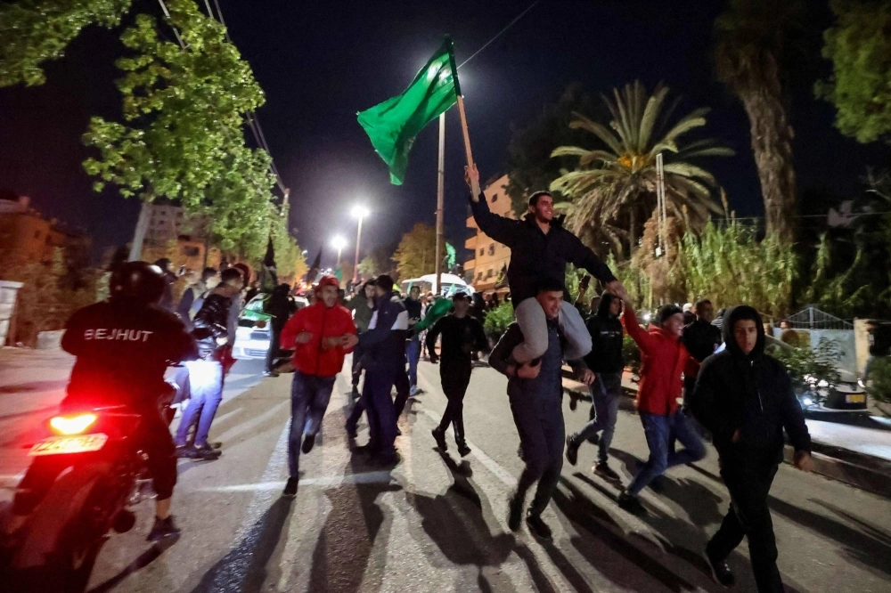 A newly released prisoner waves the Hamas flag during a welcome ceremony following the release of Palestinian prisoners from Israeli jails in exchange for Israeli hostages held in the Gaza Strip by the Palestinian militant group since the Oct. 7 attacks, in Ramallah in the occupied West Bank early on Friday. A newly released prisoner waves the Hamas flag during a welcome ceremony following the release of Palestinian prisoners from Israeli jails in exchange for Israeli hostages held in the Gaza Strip by the Palestinian militant group since the Oct. 7 attacks, in Ramallah in the occupied West Bank early on Friday.