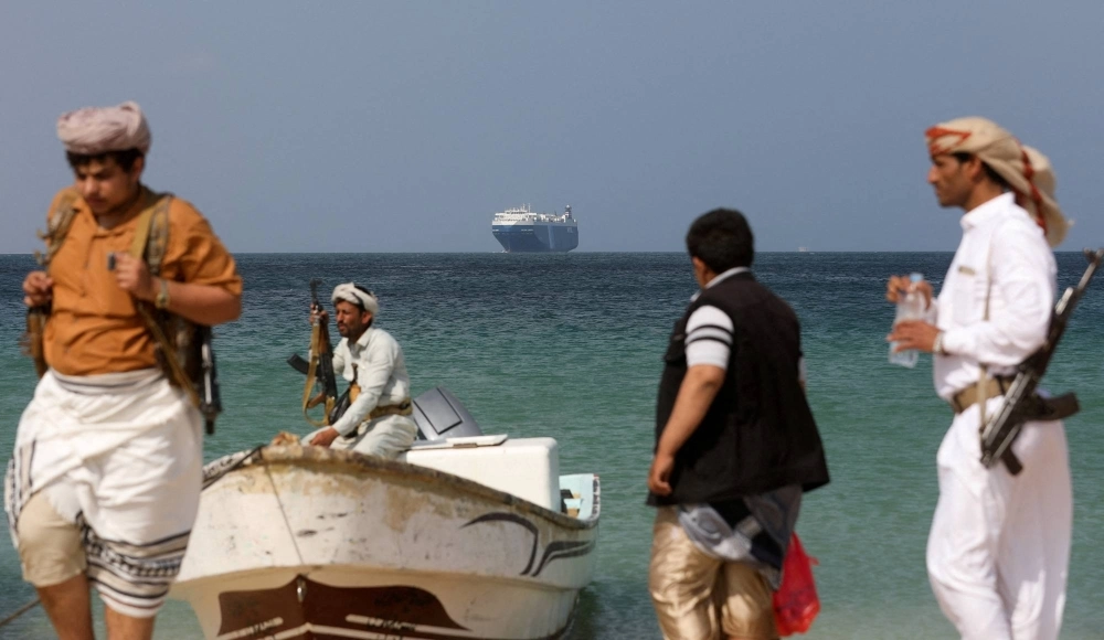Armed men stand on a beach as the Galaxy Leader commercial ship, seized by Yemen's Houthis last month, is anchored off the coast of al-Salif, Yemen, on Dec. 5. Armed men stand on a beach as the Galaxy Leader commercial ship, seized by Yemen's Houthis last month, is anchored off the coast of al-Salif, Yemen, on Dec. 5.